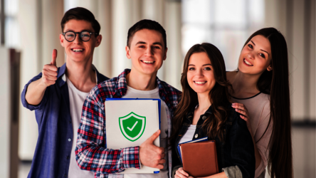 vier junge Studierende lächeln, einer zeigt Daumen hoch